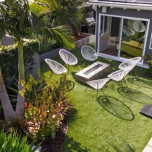 a photo of a luxurious artificial turf in a beautiful backyard with a pool and outdoor dining