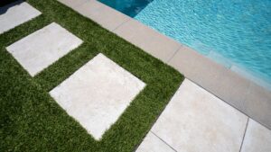 a photo of pavers in artificial grass beside a pool